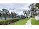 View of community tennis courts with manicured landscaping, black chain-link fence, and paved walking path through green space at 4448 Pinebark Ave # 56-1, Orlando, FL 32811