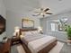 Cozy bedroom featuring a wooden bed frame, plush bedding, ceiling fan, and a large window at 662 Lake Dr, Altamonte Springs, FL 32701