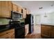 A kitchen featuring wood cabinetry, black appliances and countertops, plus tile accents at 6801 County Rd 665, Bushnell, FL 33513
