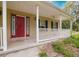 The front porch features a concrete floor, a white fence, a ceiling fan, and a red front door at 6801 County Rd 665, Bushnell, FL 33513