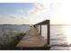 Wooden dock stretching into a serene lake under a sunny sky at 9130 Laws Rd, Clermont, FL 34714