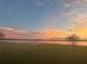 Serene sunset view over the lake, featuring a wooden dock and expansive green space at 9130 Laws Rd, Clermont, FL 34714