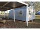 Side view of gray shed, including windows, and a carport structure with a boat next to it at 9130 Laws Rd, Clermont, FL 34714