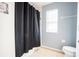 Cozy bathroom with a toilet, window, and a shower with a black shower curtain at 9228 Halsey Dr, Groveland, FL 34736