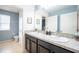Well-lit bathroom with double sinks, light blue walls, and tile flooring at 9228 Halsey Dr, Groveland, FL 34736