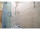 Modern walk-in shower with glass door, beige marble-look tile, and dark river rock floor at 9228 Halsey Dr, Groveland, FL 34736