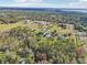 A vast aerial view reveals a house nestled amidst a dense forest, with expansive lawns and clear blue skies above at 1220 Lake Mills Rd, Chuluota, FL 32766