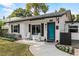 Charming home featuring rocking chairs on the front porch, a blue door, and beautiful landscaping at 1410 Osceola Ct, Orlando, FL 32806