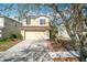 Two-story home with a beige exterior, two-car garage, small garden and a cement driveway at 15323 Torpoint Rd, Winter Garden, FL 34787