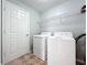 Bright laundry room with tiled floor, white washer, dryer, and shelving at 15323 Torpoint Rd, Winter Garden, FL 34787