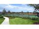 Beautiful tennis court with pristine green surface and secure fencing surrounded by lush landscaping at 15772 Murcott Harvest Loop, Winter Garden, FL 34787