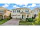 Charming two-story home featuring a brick driveway, manicured lawn, and a welcoming front porch with blue door at 17846 Adrift Rd, Winter Garden, FL 34787