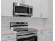 Close-up of a stainless steel range and microwave paired with quartz counters and tile backsplash at 205 Famagusta Dr, Davenport, FL 33896