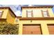 A closeup, detailed exterior view of a mustard colored townhouse showing garage and front window details at 2344 Aloha Bay Ct, Ocoee, FL 34761