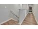 Hallway with wood floors and white railings that lead to a bedroom at the end of the hall at 3086 Fieldwood Cir, St Cloud, FL 34772