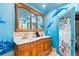 Nautical bathroom featuring a carved vanity with dual sinks, marble countertop, and whimsical dolphin art at 331 Bay St, Auburndale, FL 33823