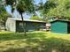 View of the side of the green home, showing a small wood deck and matching storage shed at 435 Pleasant St, Lake Helen, FL 32744