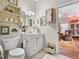 Small bathroom with tiled floors, white vanity, framed mirror and medicine cabinet and open shelving at 5150 Banana Point Dr, Okahumpka, FL 34762