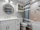 Cozy bathroom with a white vanity, round mirror, and a bathtub with gray-and-white striped shower curtain at 5150 Banana Point Dr, Okahumpka, FL 34762