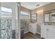 Bright bathroom featuring double sink vanities, wood-look flooring, and updated tiled shower with glass doors at 5173 Clarion Oaks Dr, Orlando, FL 32808