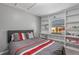 Bedroom with a grey headboard, built in shelving, and a window with blinds looking out to palm trees at 5173 Clarion Oaks Dr, Orlando, FL 32808