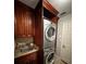 Laundry room featuring stacked washer and dryer, sink, granite countertop, and cherry cabinets at 5337 Watervista Dr, Orlando, FL 32821