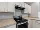 Close-up of stove with stainless steel hood and white cabinets at 6745 Huntleigh Hammock Rd, Harmony, FL 34773