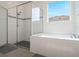 Bathroom with a clear glass shower and a soaking tub beneath a window at 739 Annabell Ridge Rd, Minneola, FL 34715