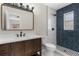 Modern bathroom featuring a wooden vanity with a sink, a large mirror, and a shower with blue tile accents at 7427 Houston E Ct, Winter Park, FL 32792