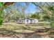 Inviting single-story home with white siding and black trim nestled among mature trees on a grassy lawn at 850 Rosalia Dr, Sanford, FL 32771