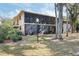 Exterior view of the screened patios of this multi-Gathering home with mature trees surrounding the lawn at 120 Hibiscus Woods Ct # 13B, Deltona, FL 32725