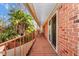 Long balcony with brick walls, wood floors and metal railings looking out onto lush greenery at 127 Georgetown Dr # 127, Casselberry, FL 32707