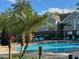 Community swimming pool with palm trees, lounge chairs, and shade umbrellas at 13028 Plantation Park Cir # 1218, Orlando, FL 32821