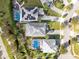 A bird's-eye view showcases three homes, with pools and solar panels, in a lush, green neighborhood at 1440 Pro Shop Ct, Davenport, FL 33896