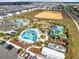 Aerial view of a community pool and recreation area with waterslides, lounge chairs, and lush landscaping at 1440 Pro Shop Ct, Davenport, FL 33896