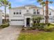 Charming two-story home with a manicured front yard and a two-car garage, enhanced by lush landscaping and tall palm trees at 1440 Pro Shop Ct, Davenport, FL 33896