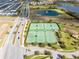 Aerial view of well-maintained tennis courts, a pond, and a neighborhood in the background at 1440 Pro Shop Ct, Davenport, FL 33896
