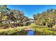 A serene backyard view showcasing mature trees, a pond with lily pads, and a wooden dock at 1461 Helena Ct, Deltona, FL 32725