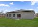 A backyard with a well-manicured lawn, a sliding glass door, and three windows under a blue sky at 14889 Sw 46Th Ct, Ocala, FL 34473