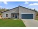 Charming single-story home featuring a blue garage door, lush green lawn, and modern architectural design at 14889 Sw 46Th Ct, Ocala, FL 34473