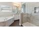 Bright bathroom with a glass-enclosed shower, soaking tub, vanity with granite counters at 1595 Juniper Hammock St, Winter Garden, FL 34787