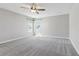 Spacious bedroom with neutral gray carpeting, ceiling fan, and natural light from two sunny windows at 1595 Juniper Hammock St, Winter Garden, FL 34787