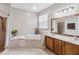 Bright bathroom featuring a soaking tub, tiled shower, and double vanity with wooden cabinetry at 18468 Sabal St, Orlando, FL 32833