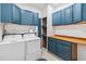 Well-organized laundry room with washer, dryer, blue cabinets, built-in shelving, and tiled floors at 18468 Sabal St, Orlando, FL 32833