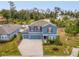 Aerial view of a two-story blue home with a well-manicured lawn and a wooded backdrop at 2067 Buckhanon Trl, Deland, FL 32720