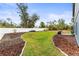 Backyard view featuring a manicured lawn, mulch landscaping, and a white vinyl fence under a blue sky at 2067 Buckhanon Trl, Deland, FL 32720