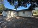 Exterior view of home showing block construction, small window, neutral paint color, and tree coverage at 220 Palm Ave, Auburndale, FL 33823