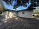 Exterior view of home showing block construction, small window, neutral paint color, and tree coverage at 220 Palm Ave, Auburndale, FL 33823