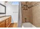 Bathroom featuring tiled tub and shower with a small window, and a wooden vanity with a decorative mirror at 2923 Cornell Ave, Orlando, FL 32804