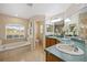 Bright bathroom with a soaking tub, double sinks, wood cabinets and an arched window at 330 Hickory Springs Ct, Debary, FL 32713